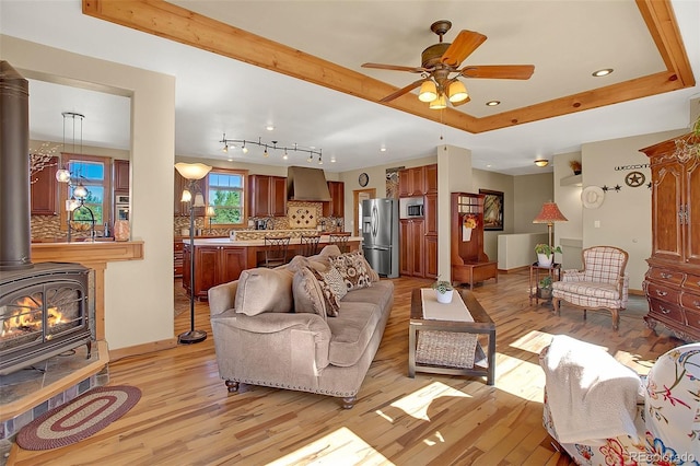 living room featuring ceiling fan, light hardwood / wood-style flooring, and a wood stove