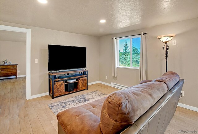 living room featuring a baseboard heating unit, light hardwood / wood-style floors, and a textured ceiling