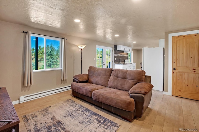 living room featuring a baseboard radiator, a textured ceiling, light hardwood / wood-style flooring, and sink