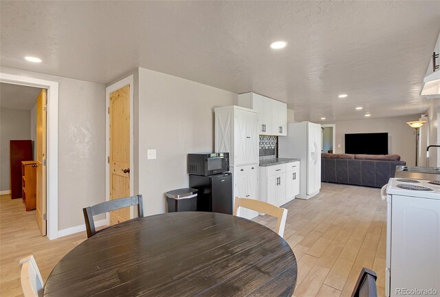 dining area with a textured ceiling and light hardwood / wood-style floors