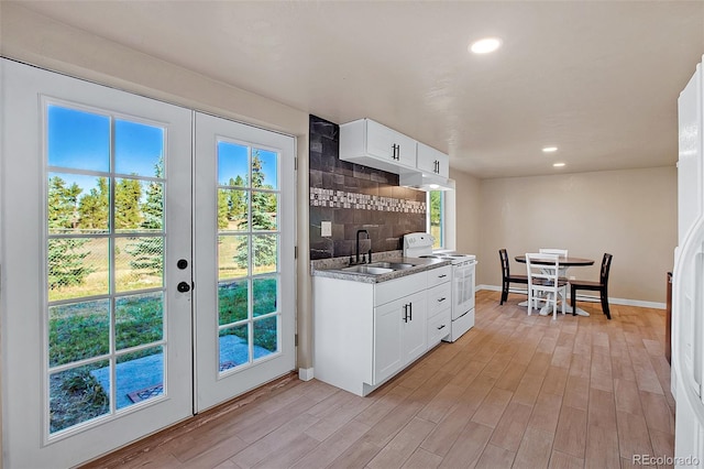 kitchen with light hardwood / wood-style flooring, sink, electric range, and white cabinetry