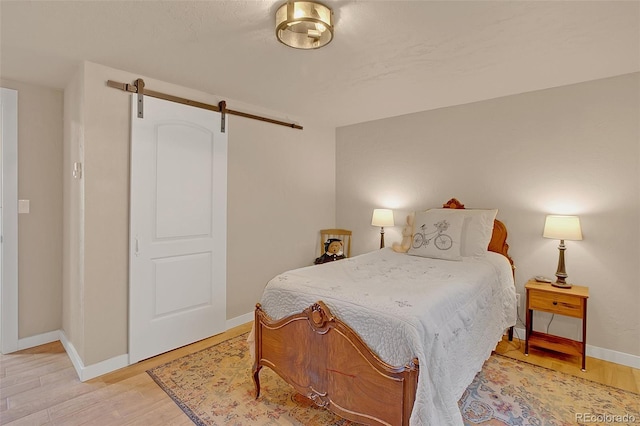 bedroom featuring light wood-type flooring and a barn door