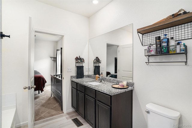 bathroom with vanity, toilet, hardwood / wood-style flooring, and a washtub