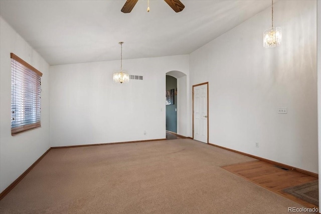 spare room with carpet floors, ceiling fan with notable chandelier, and lofted ceiling