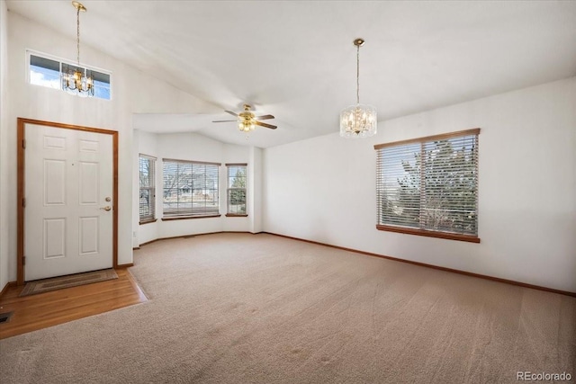 carpeted entrance foyer featuring vaulted ceiling and ceiling fan with notable chandelier