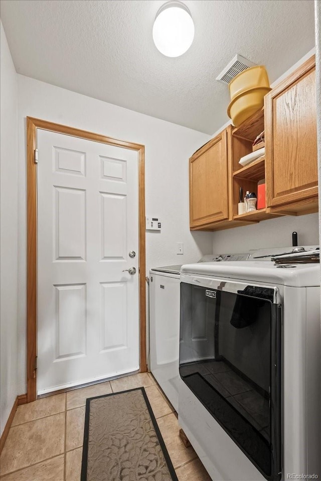 1434 Hickory Dr, Erie, CO 80516 - laundry area featuring light tile patterned flooring, washer and dryer, a textured ceiling, and cabinets