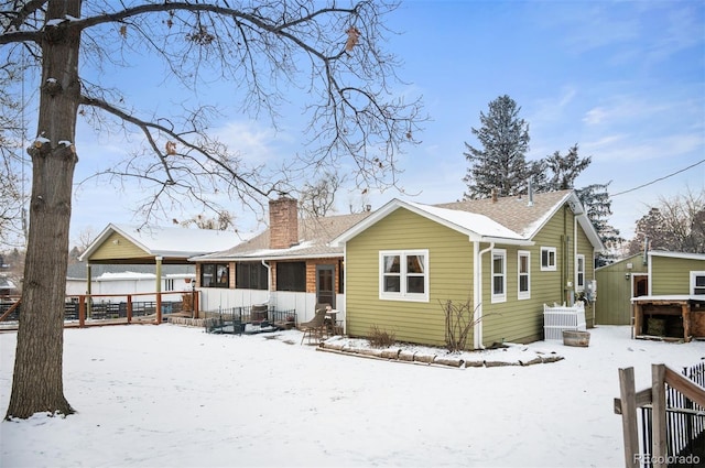 snow covered back of property featuring fence and a chimney