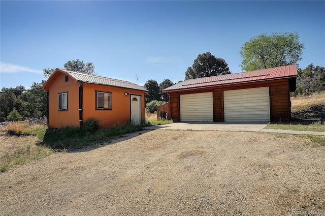 view of front of home with a garage and an outbuilding