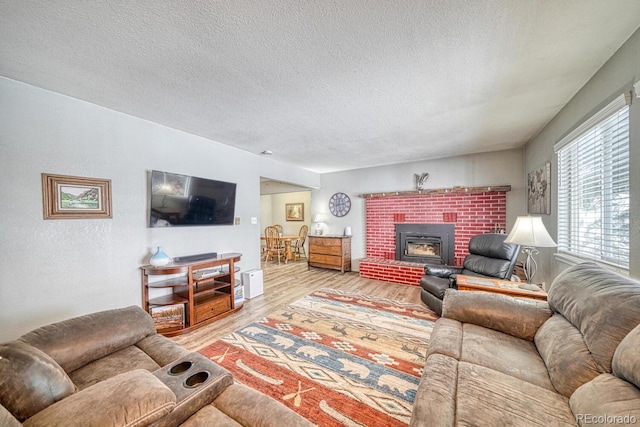 living room featuring a fireplace, light hardwood / wood-style floors, and a textured ceiling