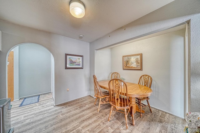 dining room with a textured ceiling and light hardwood / wood-style floors