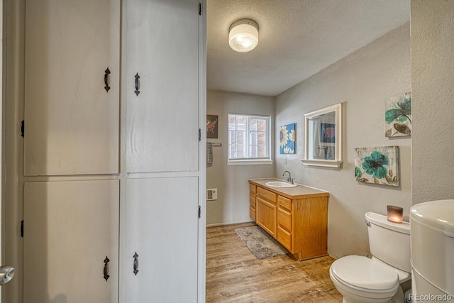 bathroom featuring hardwood / wood-style floors, vanity, a textured ceiling, and toilet