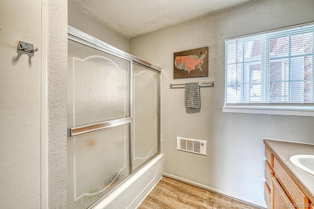 bathroom featuring vanity, wood-type flooring, shower / bath combination with glass door, and a textured ceiling