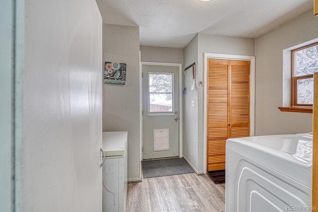 laundry area featuring a textured ceiling, washer and dryer, and light hardwood / wood-style flooring