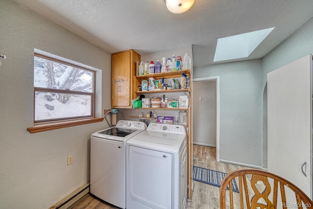 laundry area with cabinets, a textured ceiling, a skylight, independent washer and dryer, and light hardwood / wood-style flooring