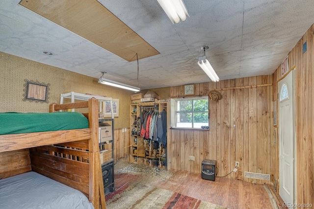 bedroom featuring hardwood / wood-style floors, wood walls, and a closet