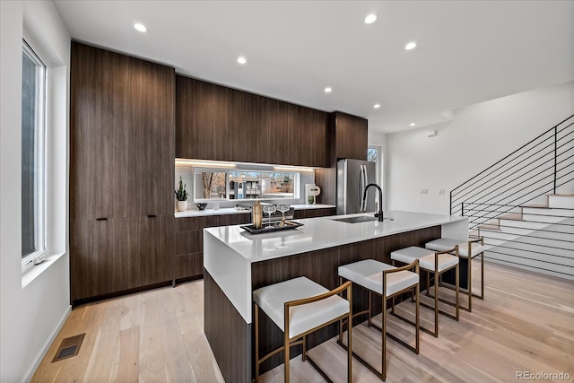 kitchen with light hardwood / wood-style flooring, stainless steel fridge, a kitchen breakfast bar, and a kitchen island