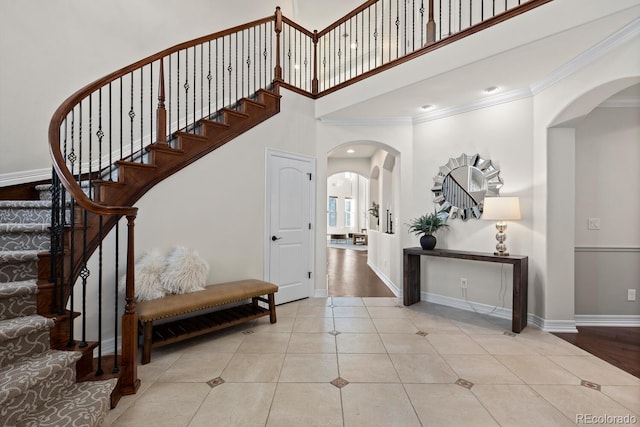 771 Braesheather Pl, Highlands Ranch, CO 80126 - staircase featuring a towering ceiling, crown molding, tile patterned flooring, arched walkways, and baseboards