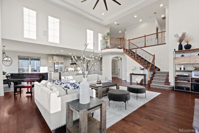 771 Braesheather Pl, Highlands Ranch, CO 80126 - living area with dark wood finished floors, crown molding, a towering ceiling, arched walkways, and stairway