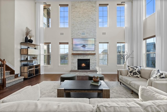 771 Braesheather Pl, Highlands Ranch, CO 80126 - living room featuring a stone fireplace, wood finished floors, baseboards, and a high ceiling