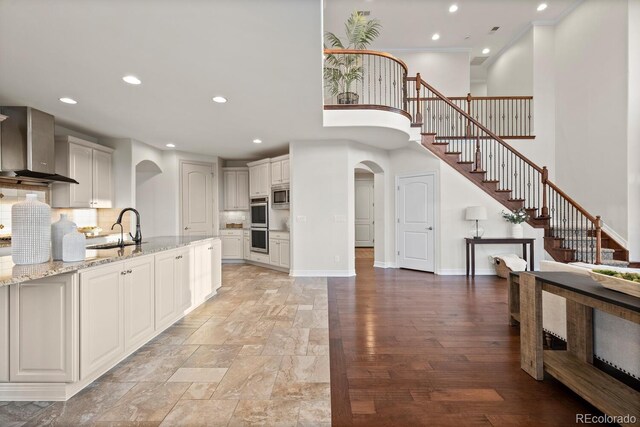 771 Braesheather Pl, Highlands Ranch, CO 80126 - kitchen featuring a sink, wall chimney exhaust hood, arched walkways, appliances with stainless steel finishes, and recessed lighting