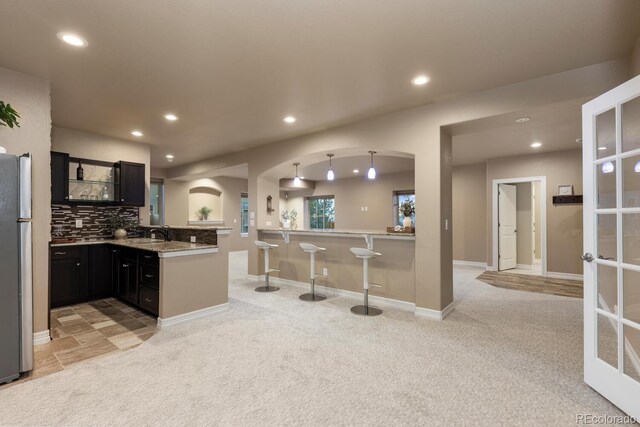 771 Braesheather Pl, Highlands Ranch, CO 80126 - kitchen with a peninsula, freestanding refrigerator, arched walkways, and light colored carpet
