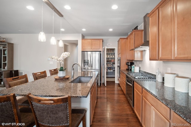 kitchen featuring a kitchen breakfast bar, appliances with stainless steel finishes, dark wood-type flooring, wall chimney range hood, and a center island with sink