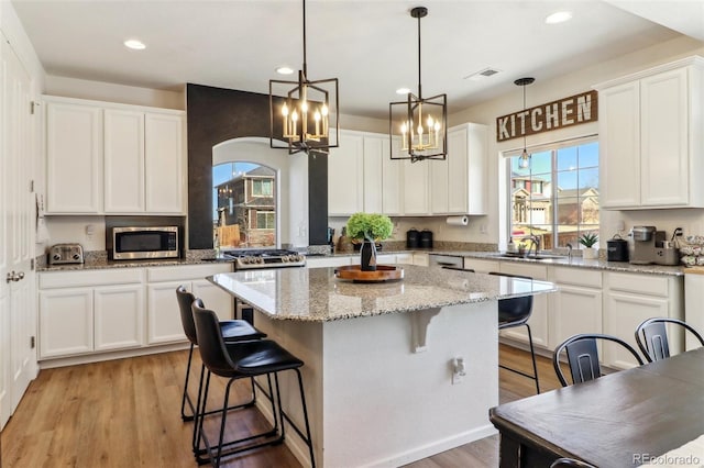 kitchen featuring white cabinetry, a kitchen island, and stainless steel microwave