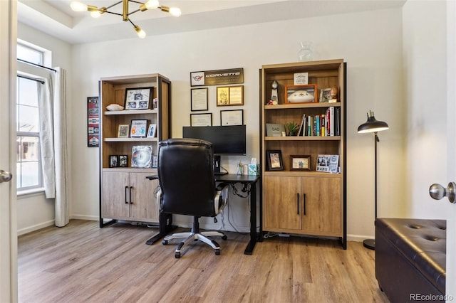 office space with light wood-style flooring, baseboards, and a notable chandelier