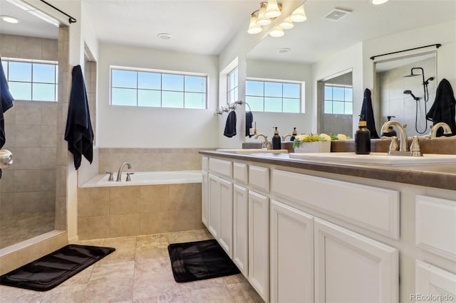 bathroom featuring visible vents, a tile shower, and a sink