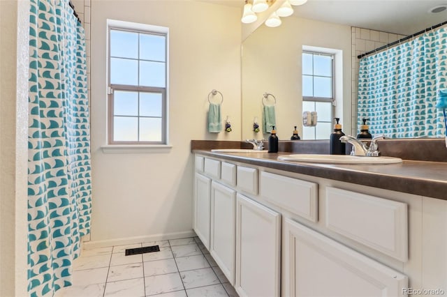 full bath with a wealth of natural light, a sink, and double vanity