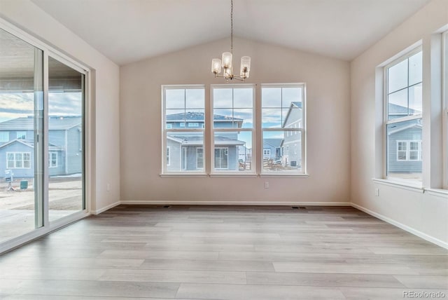 unfurnished dining area featuring light hardwood / wood-style flooring, a healthy amount of sunlight, lofted ceiling, and an inviting chandelier