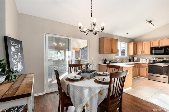 dining room featuring an inviting chandelier, baseboards, light wood-style floors, and lofted ceiling