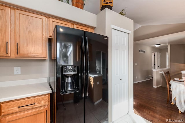 kitchen featuring visible vents, lofted ceiling, black fridge with ice dispenser, and light countertops