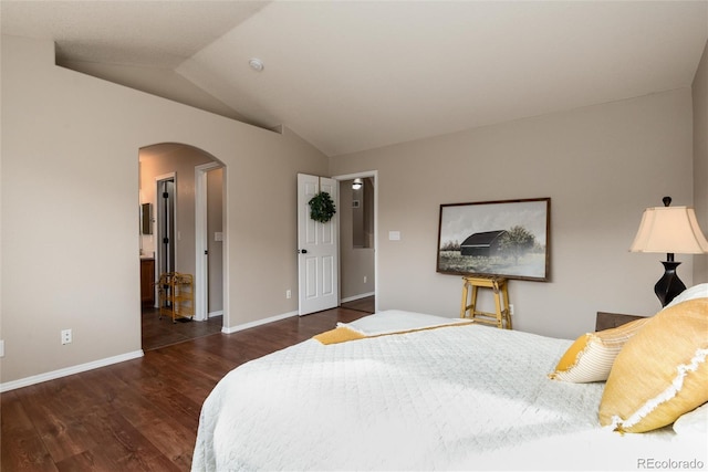 bedroom featuring lofted ceiling, wood finished floors, arched walkways, and baseboards