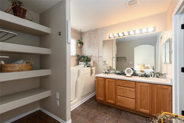 ensuite bathroom with a sink, visible vents, double vanity, and tile patterned flooring