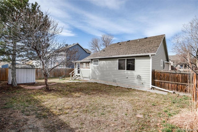 rear view of property featuring entry steps, an outdoor structure, a storage unit, and a fenced backyard