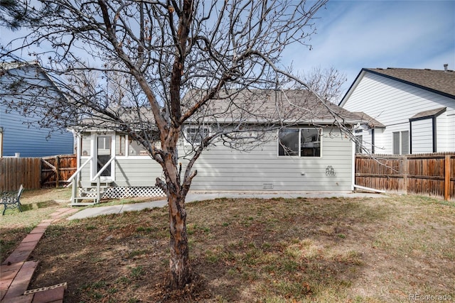 back of house featuring a lawn, a fenced backyard, and entry steps