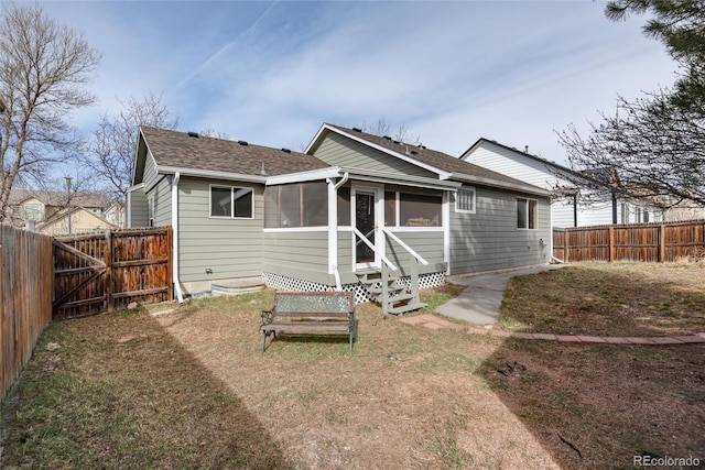 back of property featuring a lawn, a shingled roof, a fenced backyard, and a sunroom