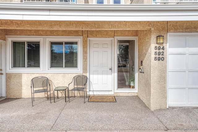 view of exterior entry featuring a garage and stucco siding