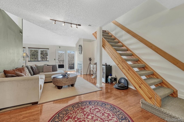 living room featuring hardwood / wood-style floors, baseboards, stairs, track lighting, and a textured ceiling