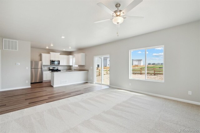 unfurnished living room with a ceiling fan, visible vents, baseboards, light carpet, and recessed lighting