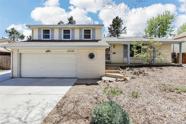 split level home featuring a porch, brick siding, driveway, and fence