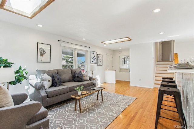 living area with a skylight, recessed lighting, and light wood-style flooring