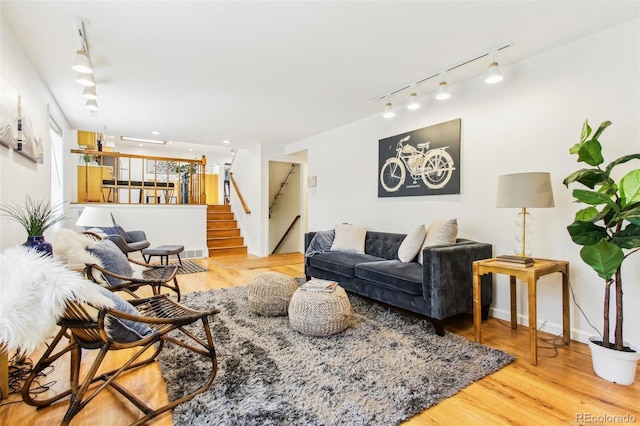 living area featuring stairway, rail lighting, and wood finished floors