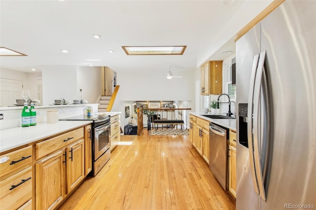 kitchen with light wood-type flooring, a sink, light countertops, stainless steel appliances, and recessed lighting