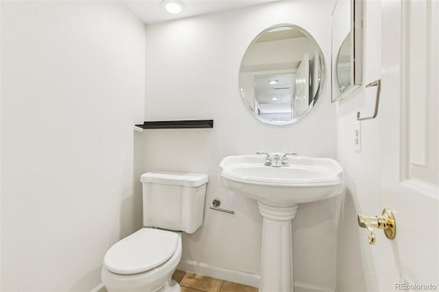 half bathroom with tile patterned floors, baseboards, and toilet