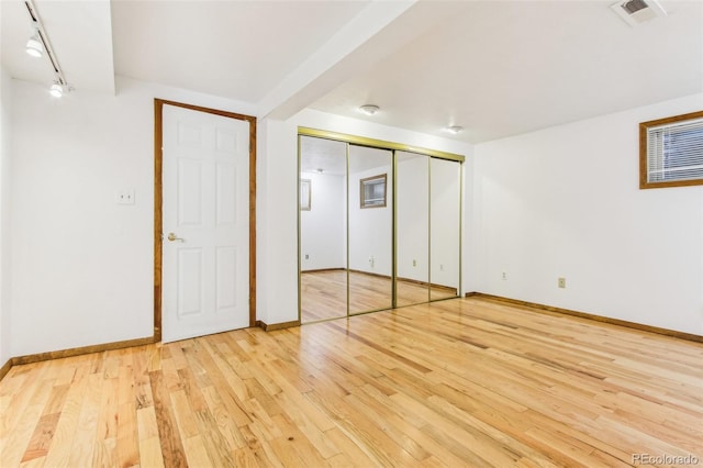 unfurnished bedroom featuring visible vents, baseboards, a closet, and hardwood / wood-style flooring