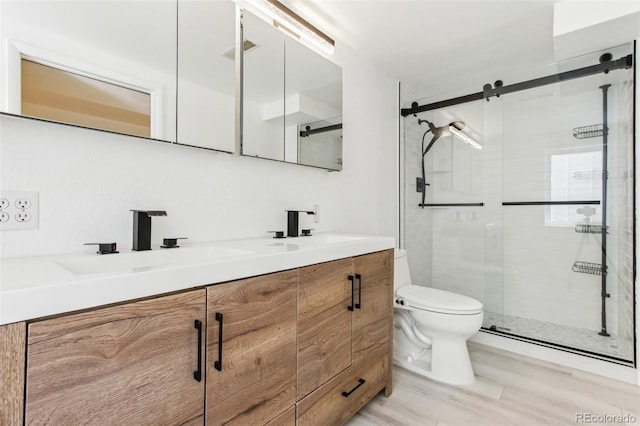 full bathroom featuring double vanity, toilet, a shower stall, and a sink