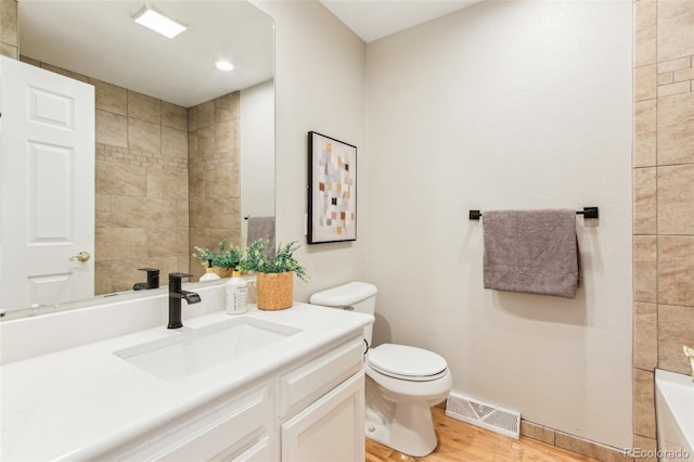 bathroom with visible vents, wood finished floors, toilet, baseboards, and a bath