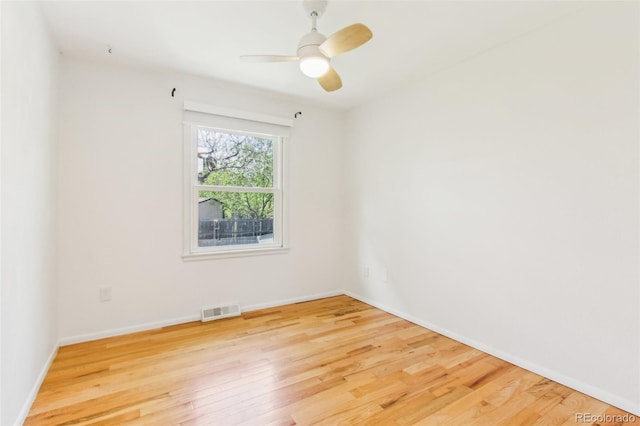 spare room with baseboards, wood finished floors, and visible vents